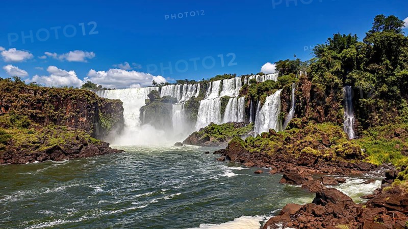 Impressive waterfalls with cascading floods and lush vegetation under a blue sky, The Iguazu Falls between Argentina and Brazil