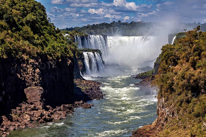Majestic waterfalls with strong flow and spray, framed by lush vegetation, The Iguazu Falls between Argentina and Brazil
