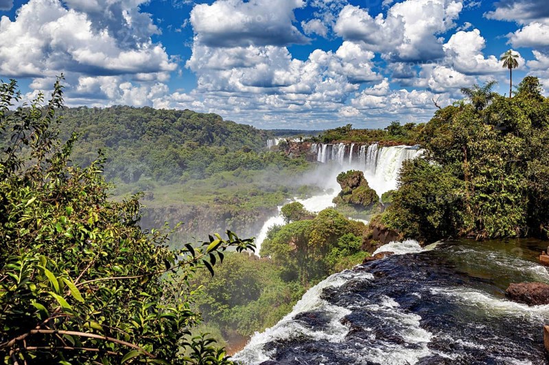 Rushing waterfall in dense vegetation under a vast sky, The Iguazu Falls between Argentina and Brazil