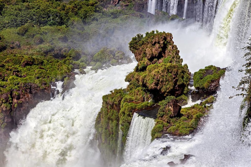 Moss-covered rocks surround a dynamic waterfall in the midst of nature, The Iguazu Falls between Argentina and Brazil