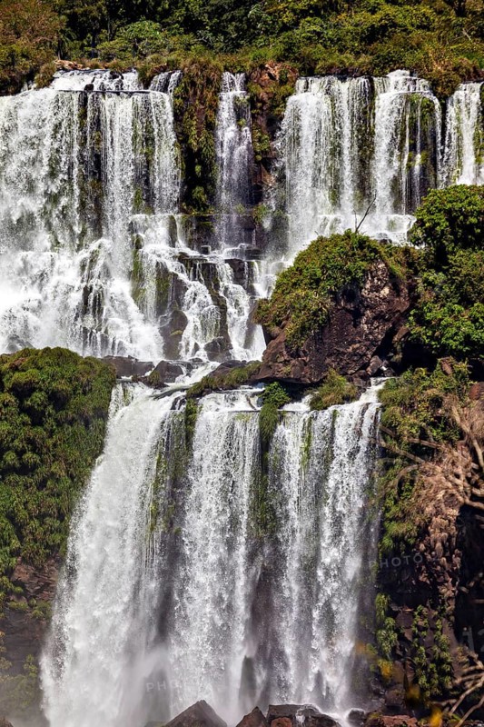 Stepped waterfall with dense vegetation on the rocks, powerful flow, The Iguazu Falls between Argentina and Brazil