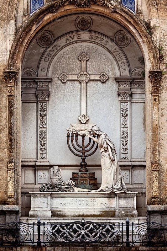 An artistically designed tomb with a statue and a cross in the centre, La Recoleta cemetery in Buenos Aires Argentina