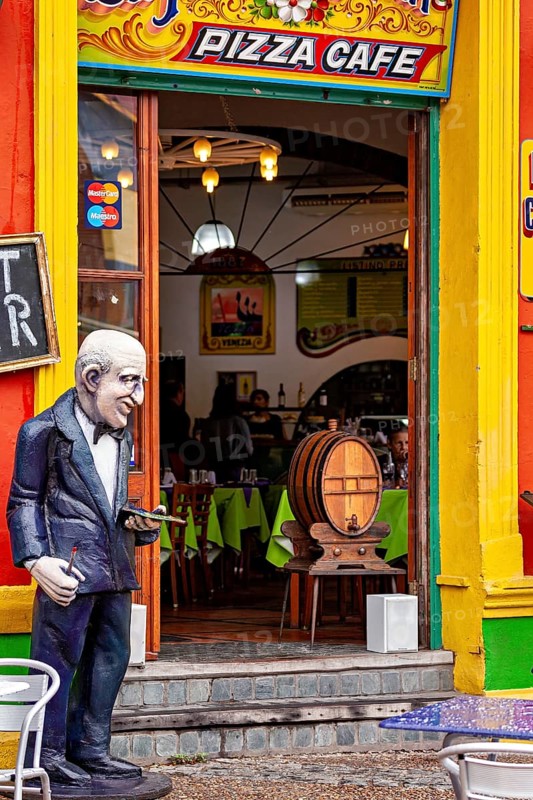 A café with a colourful façade and a sculpture in front of the entrance, inviting interior, The colourful city and tango district of La Bocca in Buenos Aires Argentina