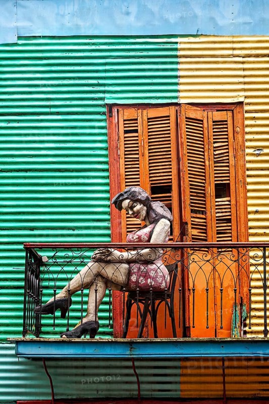Female figure on a balcony in front of a striped façade, The colourful city and tango district of La Bocca in Buenos Aires Argentina
