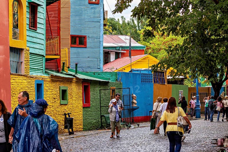 People stroll through a colourful street in a neighbourhood of colourful houses, The colourful city and tango district of La Bocca in Buenos Aires Argentina