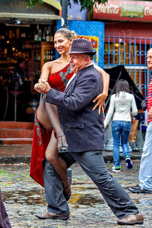 A couple happily dancing tango on a rain-soaked street in front of a café, The colourful city and tango district La Bocca in Buenos Aires Argentina