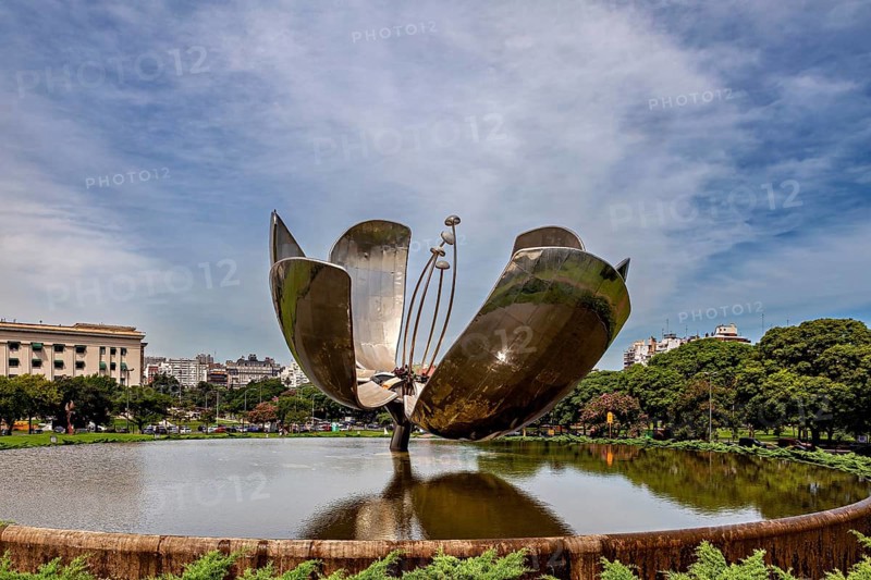 Metal flower sculpture near buildings with a cloudy sky in the background, The lotus blossom in Buenos Aires Argentina
