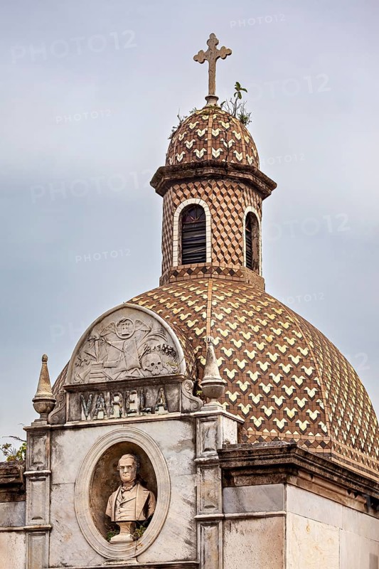 Historic structure with decorative dome, cross and a bust in an ornate relief, La Recoleta cemetery in Buenos Aires Argentina