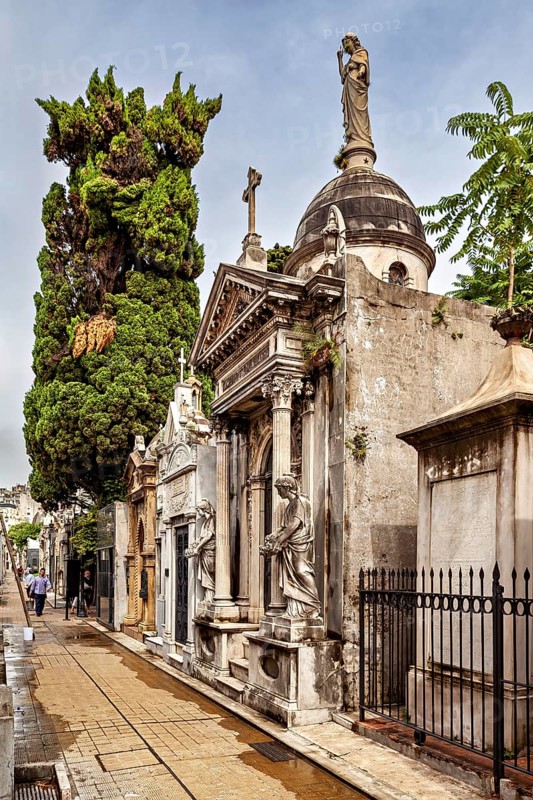 Magnificent burial site with trees and statues along a path, La Recoleta cemetery in Buenos Aires Argentina