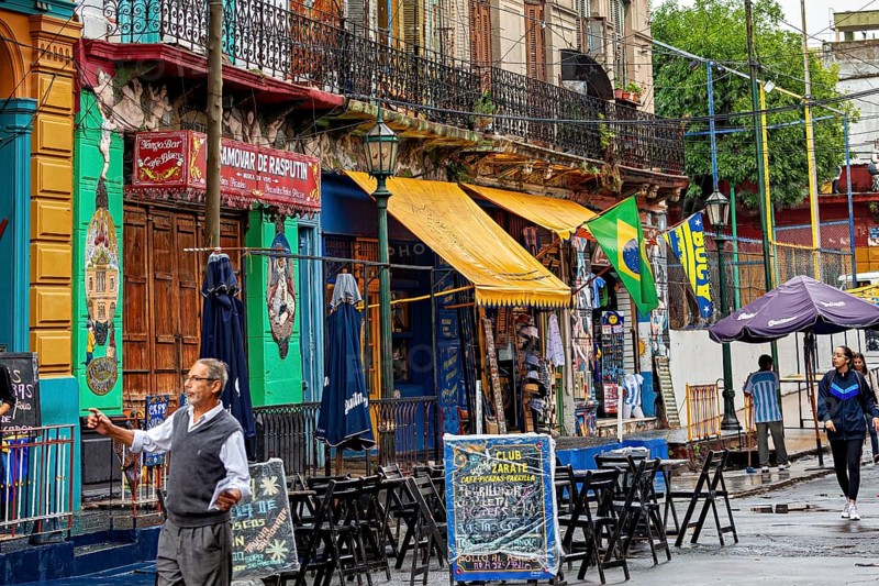 A lively street market with colourful banners and cafés, people stroll past, The colourful city and tango district of La Bocca in Buenos Aires Argentina