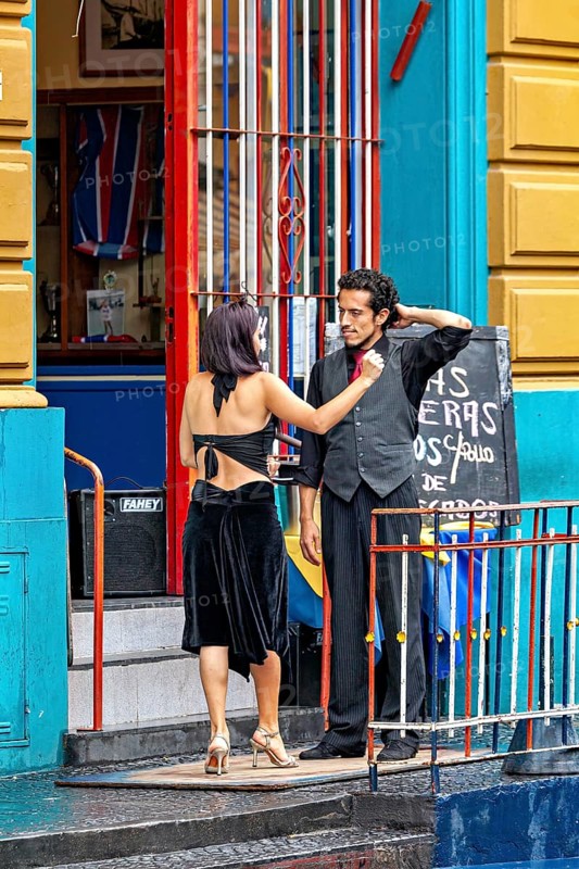 A couple discussing in front of a colourful entrance in tango clothes, the woman wears a black dress, The colourful city and tango district La Bocca in Buenos Aires Argentina