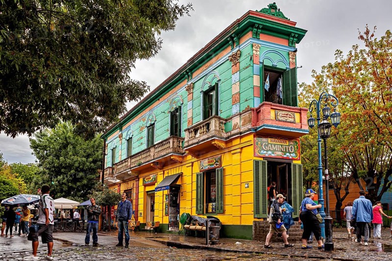 A colourful historic building with cafés attracts people on a cobbled street, The colourful city and tango district of La Bocca in Buenos Aires Argentina