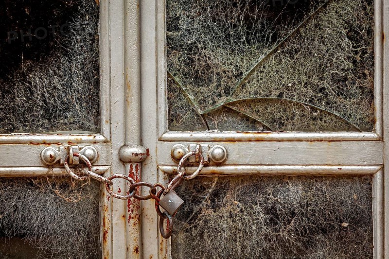 Abandoned building with a locked, rusty chain and broken window, exuding a dilapidated atmosphere, La Recoleta cemetery in Buenos Aires Argentina