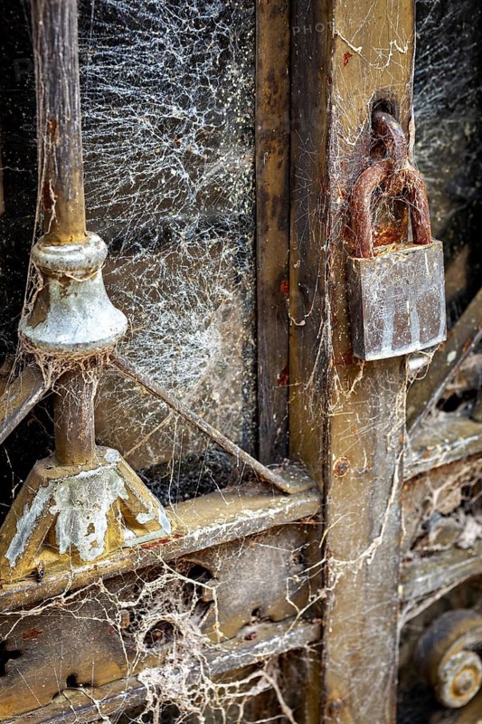 Detail of an old dilapidated door with cobwebs and a rusty lock, La Recoleta cemetery in Buenos Aires Argentina