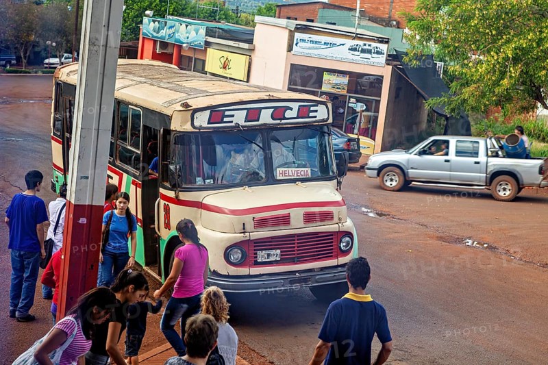 A bus stops in a suburban area, surrounded by people and vehicles, An old Mercedes bus in Argentina