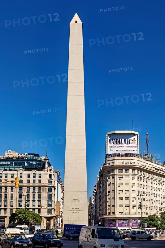 A tall obelisk stands between modern buildings under a clear blue sky, The Great Obelisk in the city of Buenos Aires Argentina