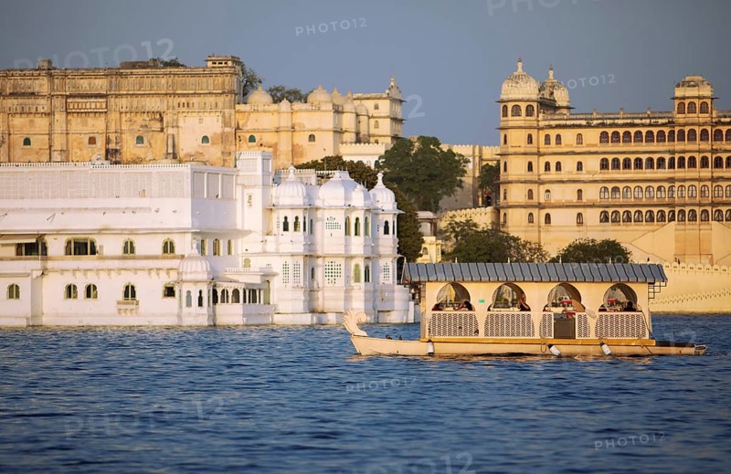 Excursion boat on Lake Pichola, behind the City Palace in the evening light, Udaipur, Rajasthan, India