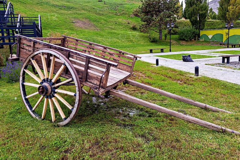 Weathered carriage on a green surface surrounded by hills and trees, Historical horse-drawn carriage or coach with wagon wheels in Patagonia