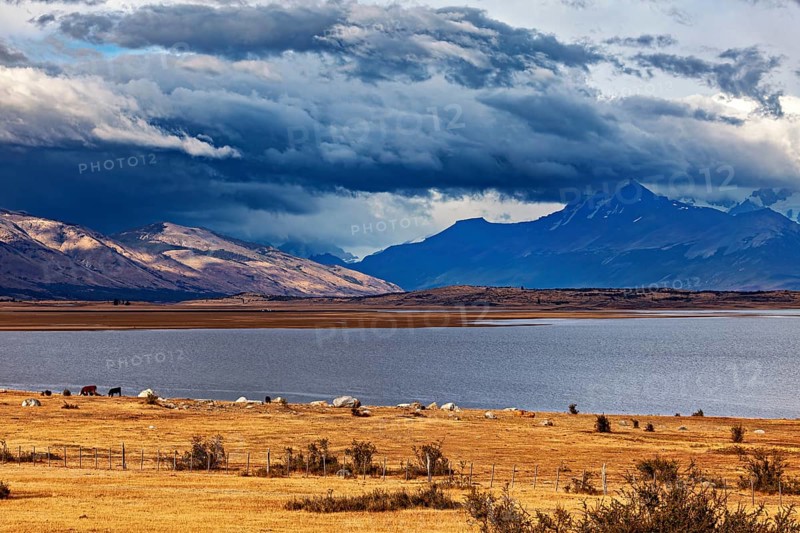 A wide lake under dramatically threatening clouds, surrounded by majestic mountains: the Patagonian landscape near El Chalten in Argentina