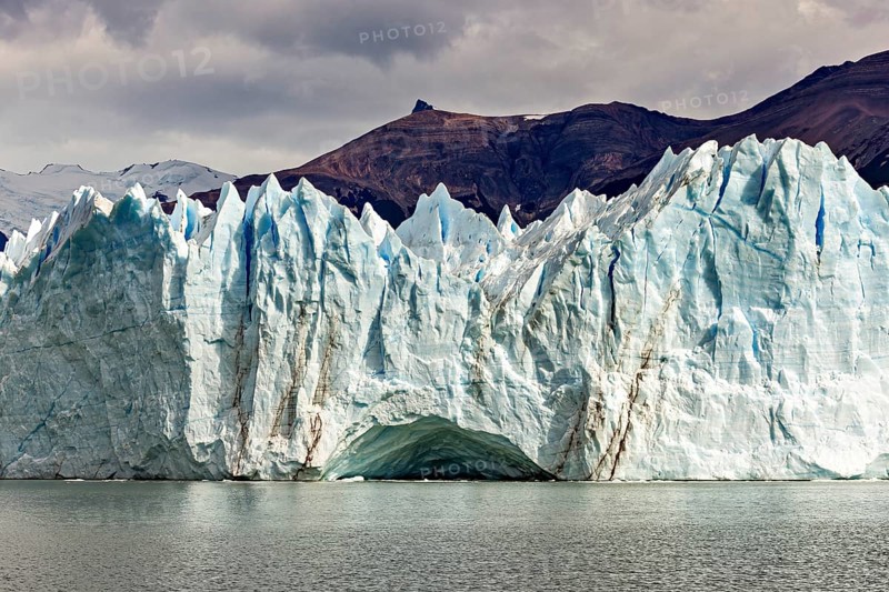 Impressive ice wall of a glacier under a cloudy sky near a mountain, The glacier of Perito Moreno in Argentina