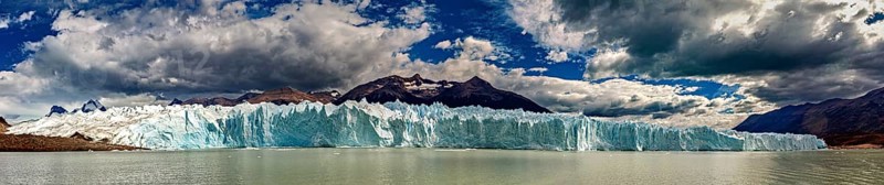 Large-scale panorama of a distant glacier with draped clouds and mountains, The glacier of Perito Moreno in Argentina