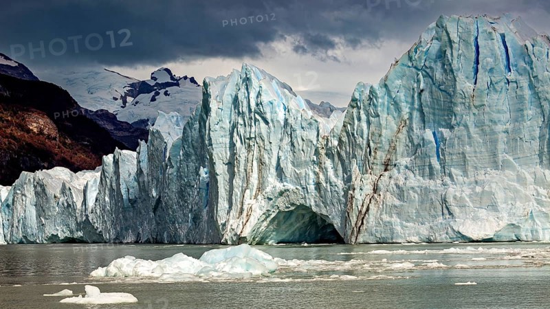 Majestic glacier in the water with dramatic clouds and mountains in the background, The Perito Moreno glacier in Argentina