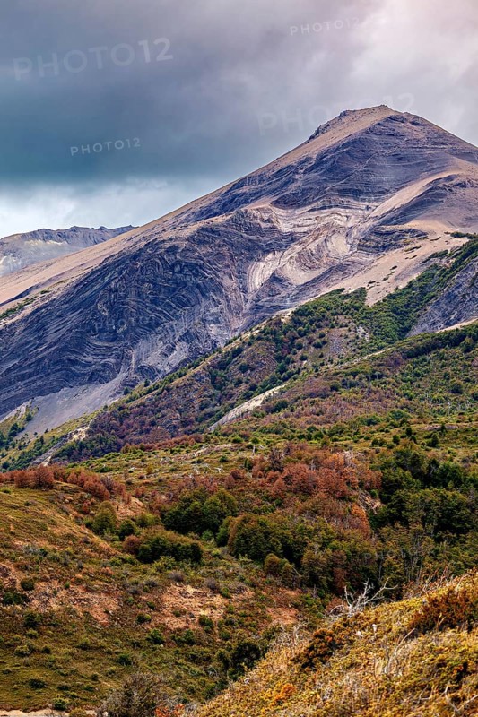 Imposing mountain with steep slopes and dense vegetation under a cloudy sky, the Patagonian landscape near El Chalten in Argentina