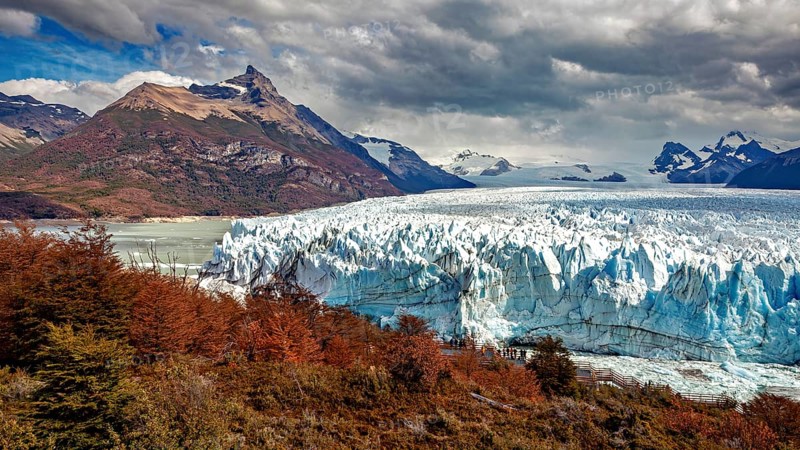 Imposing glacier front in a majestic mountain landscape with autumnal trees and dramatic skies, The Perito Moreno glacier in Argentina