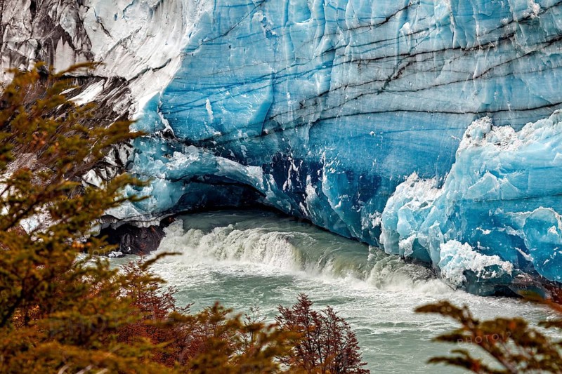 Flowing water under an impressive blue glacier wall, The Perito Moreno glacier in Argentina