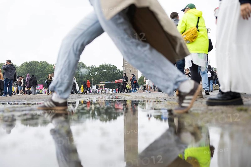Festival-goers jump over a puddle of rain at the Lollapalooza Festival in the Olympic Stadium and on the Maifeld, Berlin, 12 July 2025