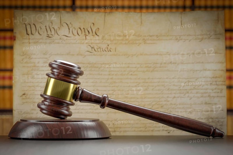 United states constitution on wall with gavel resting on table in front