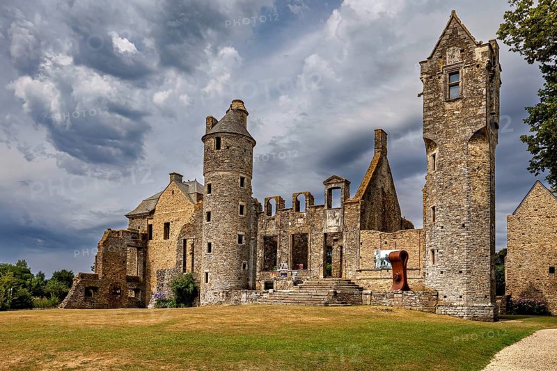 Historic castle ruins with towers under dramatic clouds, Gratot Castle in Normandy, France