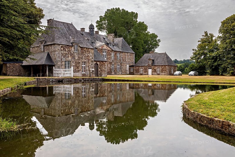 A castle with a pond in front of it, in which the building and the surrounding trees are reflected, The Abbey de La Lucerne in Normandy, France