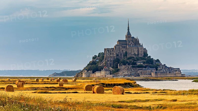 A castle with fields and bales of straw in the fading light of evening, Mont Saint Michel in Normandy, France