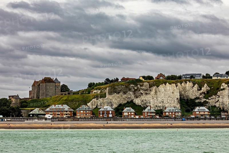 Castle on cliffs with houses on the beach, dramatic sky over coastal landscape with sea view, Dieppe Castle in Normandy, France