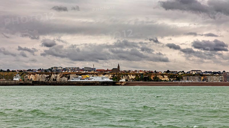 Coastal town with cliffs and a church, under a cloudy sky, The coast of Dieppe in Normandy, France