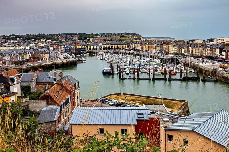View of a busy harbour town with many boats and city buildings under a cloudy sky, The harbour of Dieppe in Normandy, France