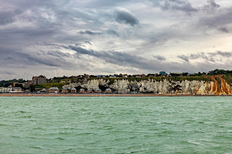 Rocky coast with houses above, under a cloudy sky, The coast of Dieppe in Normandy, France