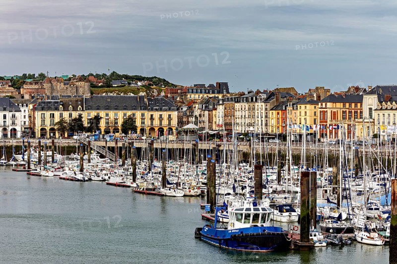 Cityscape with harbour and boats in front of a hilly backdrop under a cloudy sky, The harbour of Dieppe in Normandy, France