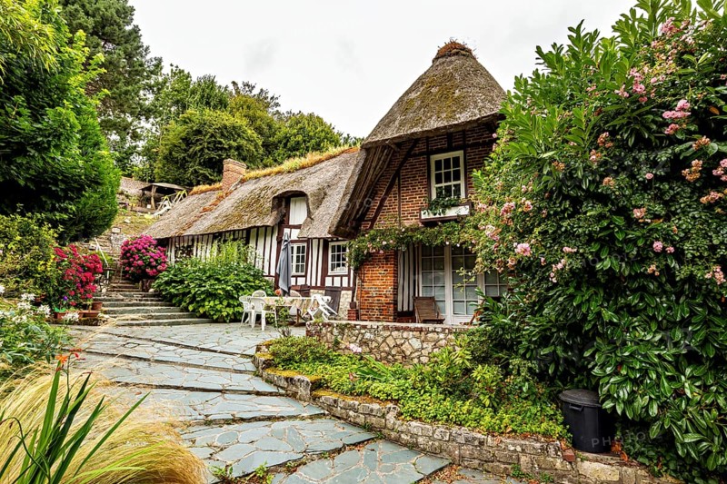 Charming thatched house in a lush garden with traditional architectural elements, the historic mill village of Veules Les Roses in Normandy, France