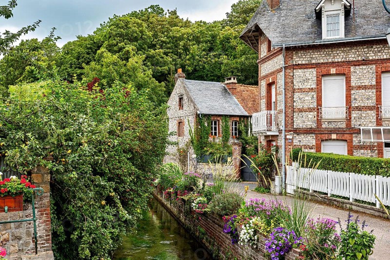 Narrow alley with brick houses and flowering canal, surrounded by rural nature, The historic mill village of Veules Les Roses in Normandy, France