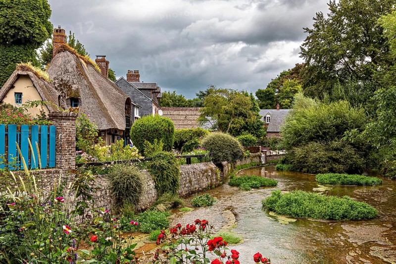 Romantic river landscape with cottages and blooming flowers under a cloudy sky, the historic mill village of Veules Les Roses in Normandy, France