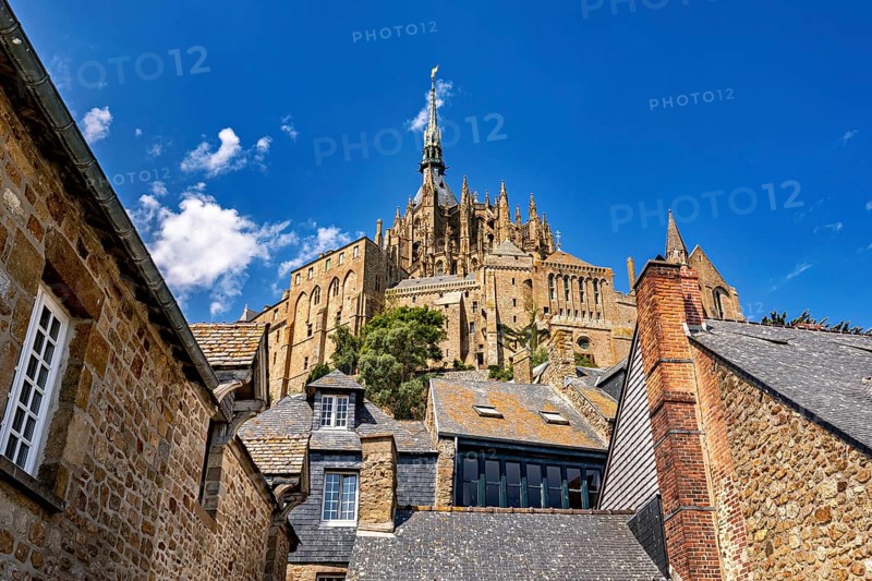 Sublime castle with Gothic towers, rising into the sky above the roofs of historic buildings, Mont Saint Michel in Normandy, France