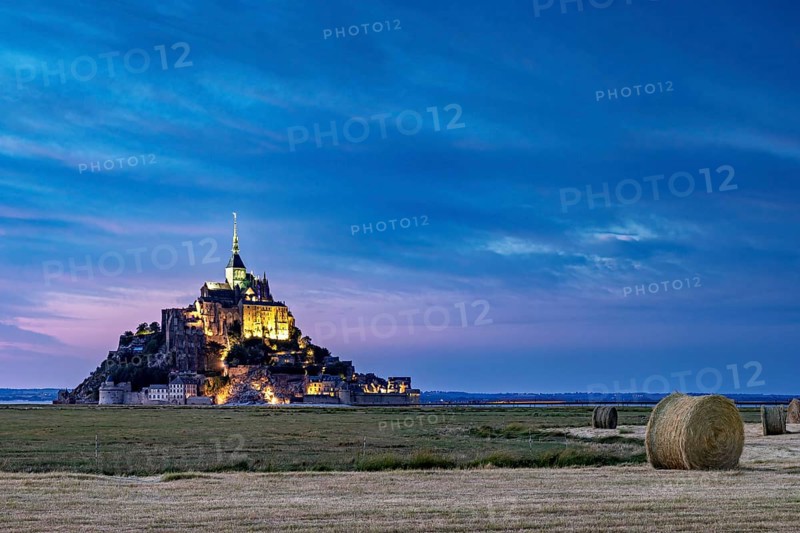 Mont Saint-Michel at dusk, illuminated with straw bales in the foreground, Mont Saint Michel in Normandy, France