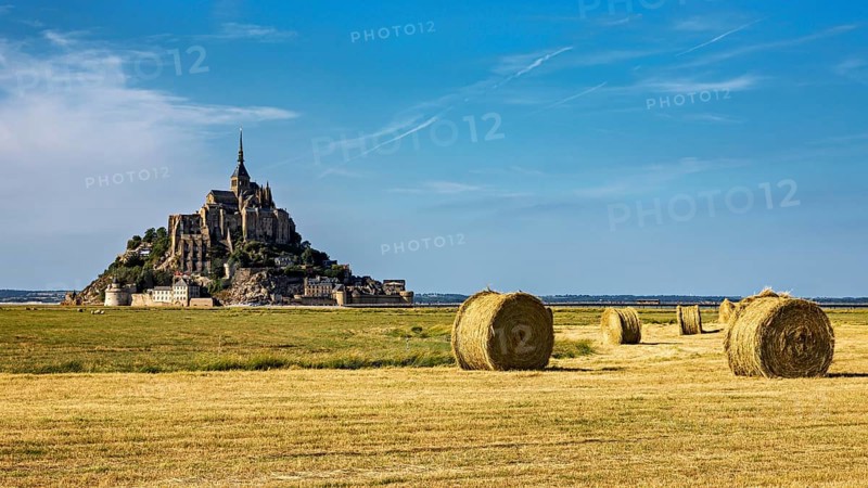 View of Mont Saint-Michel with bales of straw in a field under a clear sky, Mont Saint Michel in Normandy, France