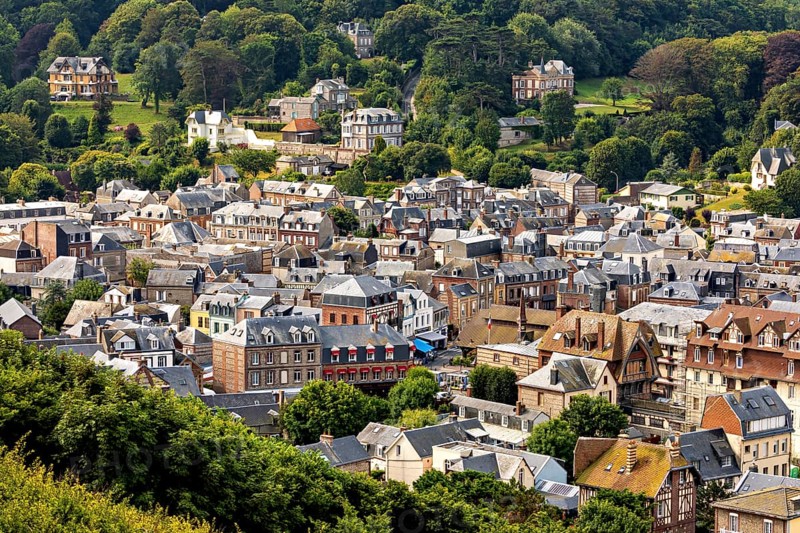 Expansive view of a town from a green hill with lots of nature, Etretat in Normandy, France