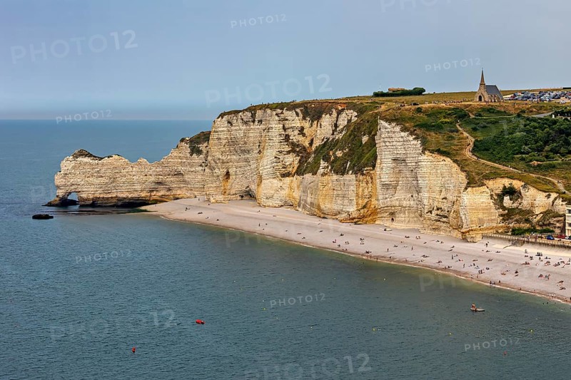 Imposing cliffs with a church at the top and a quiet beach by the sea, The cliffs and alabaster coast of Etretat in Normandy France
