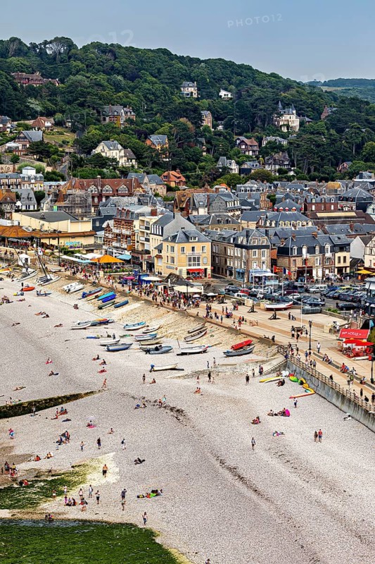 Beach scene in a coastal town with many people and boats, Etretat in Normandy, France