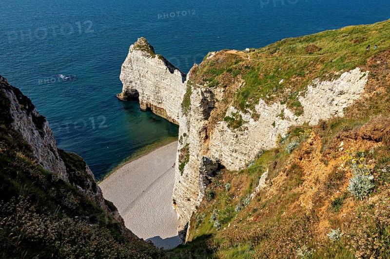 Steep rocks and cliffs with a small hidden beach by the turquoise blue sea, The cliffs and alabaster coast of Etretat in Normandy France