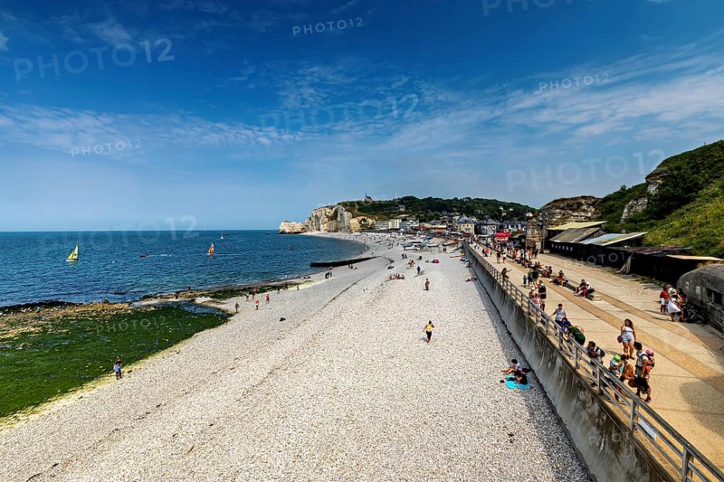 Wide beach with sea view and people walking under a blue sky, Etretat in Normandy, France